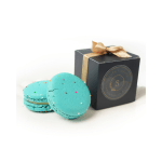 Two blue macarons beside a black gift box with a gold ribbon