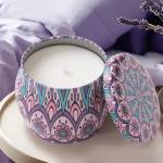 Patterned candle in a decorative tin with its lid beside it