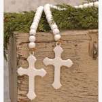 Pair of white beaded cross ornaments hanging on a rustic wooden box