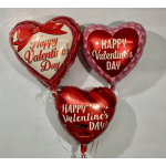 Three heart-shaped Valentine's Day balloons against a wall.