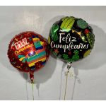 Two round birthday balloons with Spanish text against a wall