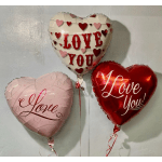 Three heart-shaped balloons with love messages on a wall