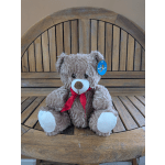 Brown teddy bear with a red ribbon sitting on a wooden chair