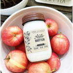 Apple-scented candle in a jar surrounded by red apples