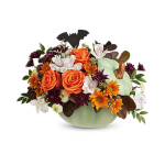 Orange roses and mixed fall flowers in a pale green pumpkin container with a bat pick