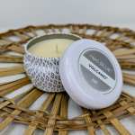 Scented candle in a patterned tin with a lid beside it