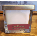 White candle in a square glass jar with a metal lid