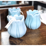 Three light blue tulip-shaped candle holders on a wooden surface