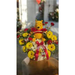 Basket arrangement with a Winnie the Pooh plush surrounded by yellow and red flowers