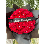 Bouquet of red roses wrapped in black paper with a Valentine's Day ribbon