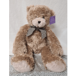 Large plush teddy bear with a checkered bow sitting on a silver surface