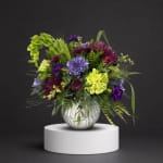 Purple and lime floral arrangement in a silver vase