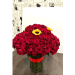 Large arrangement of red roses with yellow sunflowers in a clear glass cylinder vase with red ribbon.