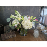 White lilies and hydrangeas in a glass vase with pink accents