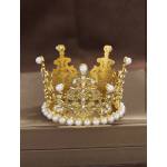 Gold jeweled crown with pearl accents on a brown box