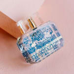 Perfume bottle with blue floral pattern on a pink background