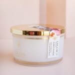 White candle jar with a gold lid and floral label