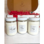 Three scented candles in glass jars with white lids, arranged in front of a gift box.