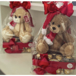 Two teddy bears wrapped in clear plastic with red bows and chocolates