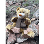 Teddy bear sitting on rocks wearing a scarf
