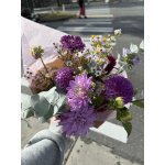 Handheld bouquet of purple flowers with small white daisies