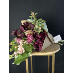Bouquet of deep burgundy and pink flowers wrapped in kraft paper