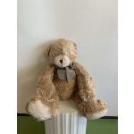 Teddy bear with a checkered bow sitting on a pedestal