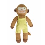 Knitted monkey plush toy in yellow overalls on a white background