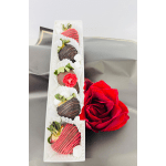 Box of chocolate-covered strawberries beside a red rose