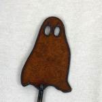 Brown ghost-shaped decorative pick on a white fabric background