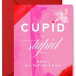 Pink Galentine's Day greeting card with white text and small cupid illustration, paired with a red envelope