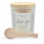 Amber Noir scented candle in a glass jar with a wooden spoon