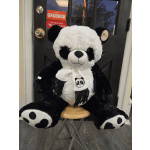 Large black-and-white panda plush toy sitting on a stool