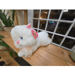 White plush cat with pink ears and a ribbon on a wooden shelf