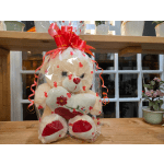 Cream teddy bear in heart-print cellophane with a red bow