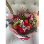 Bright bouquet of red, pink, and orange flowers wrapped in pink paper with a silver butterfly decoration.