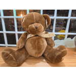 Brown teddy bear with a ribbon sitting on a wooden surface