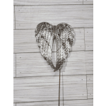 Silver decorative angel wings on a stick against a wood background