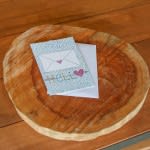 A round wicker basket holding a greeting card on a wooden surface.