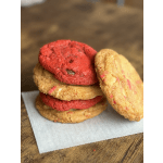 Stack of red and golden cookies on parchment paper over a wooden surface