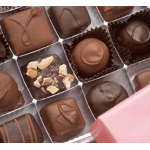 Assorted chocolates in a gift box with one piece topped with nuts