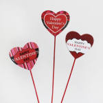 Three heart-shaped Valentine picks with red sticks and printed messages