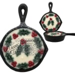Holiday candles in black cast-iron pans with holly decorations