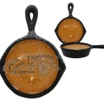 Three orange candles in black cast-iron skillet containers