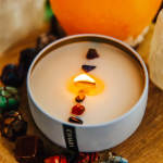 White candle in a round tin with colored stones on top