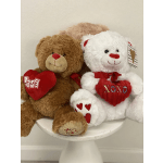 Two plush teddy bears holding red heart pillows on a white stool