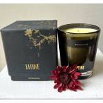 Black candle in a glass jar beside a matching box with a red flower accent