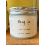 A frosted jar candle with a silver lid and Honey Bee label