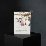 Decorative new-home card with a hummingbird, flowers, and a heart charm