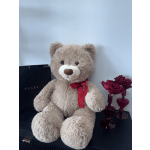 Teddy bear with a red ribbon beside a small vase of red roses